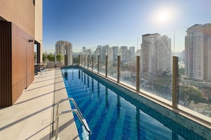 Une piscine sur le toit offrant une vue sur la ville, entourée d’immeubles de grande hauteur.