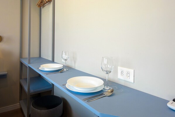 A clean, modern room with a blue countertop, a mirror, a wall socket, and a black trash bin. - Temporada Express (São Paulo)