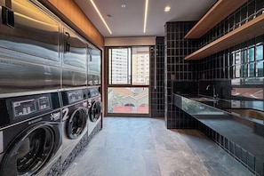 Une buanderie moderne dotée d’un lave-linge et d’un sèche-linge encastrés, d’une grande fenêtre et d’une vue sur la ville.