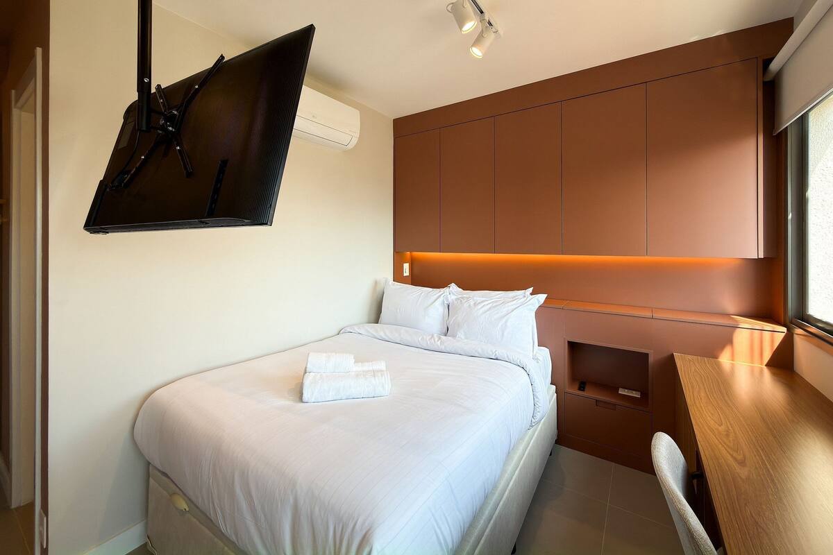 Ein modernes Hotelzimmer mit einem Bett, einem Schreibtisch und einem an der Wand befestigten Fernseher.