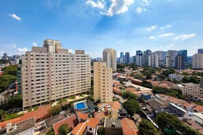 A high-rise building with multiple floors, surrounded by smaller residential buildings and greenery. - Temporada Express (São Paulo)