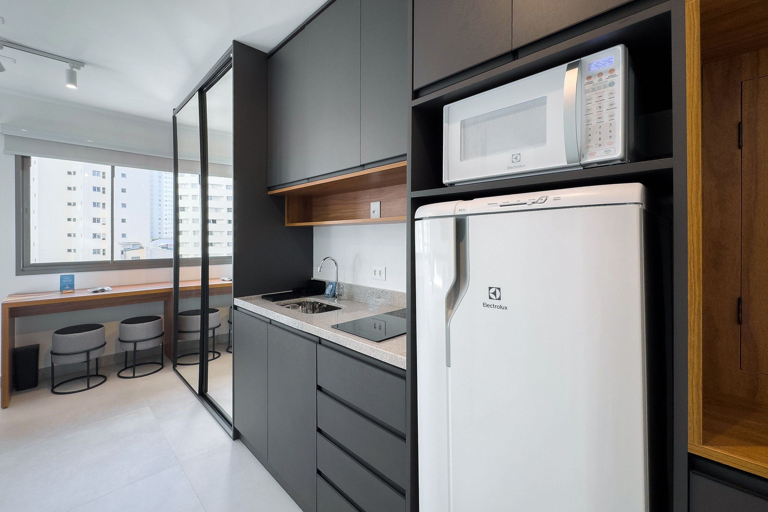 A modern kitchen with a refrigerator, microwave, and sink.