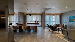 Un vaste espace de vie comprenant une table à manger, des canapés et une grande fenêtre agrémentée de rideaux.