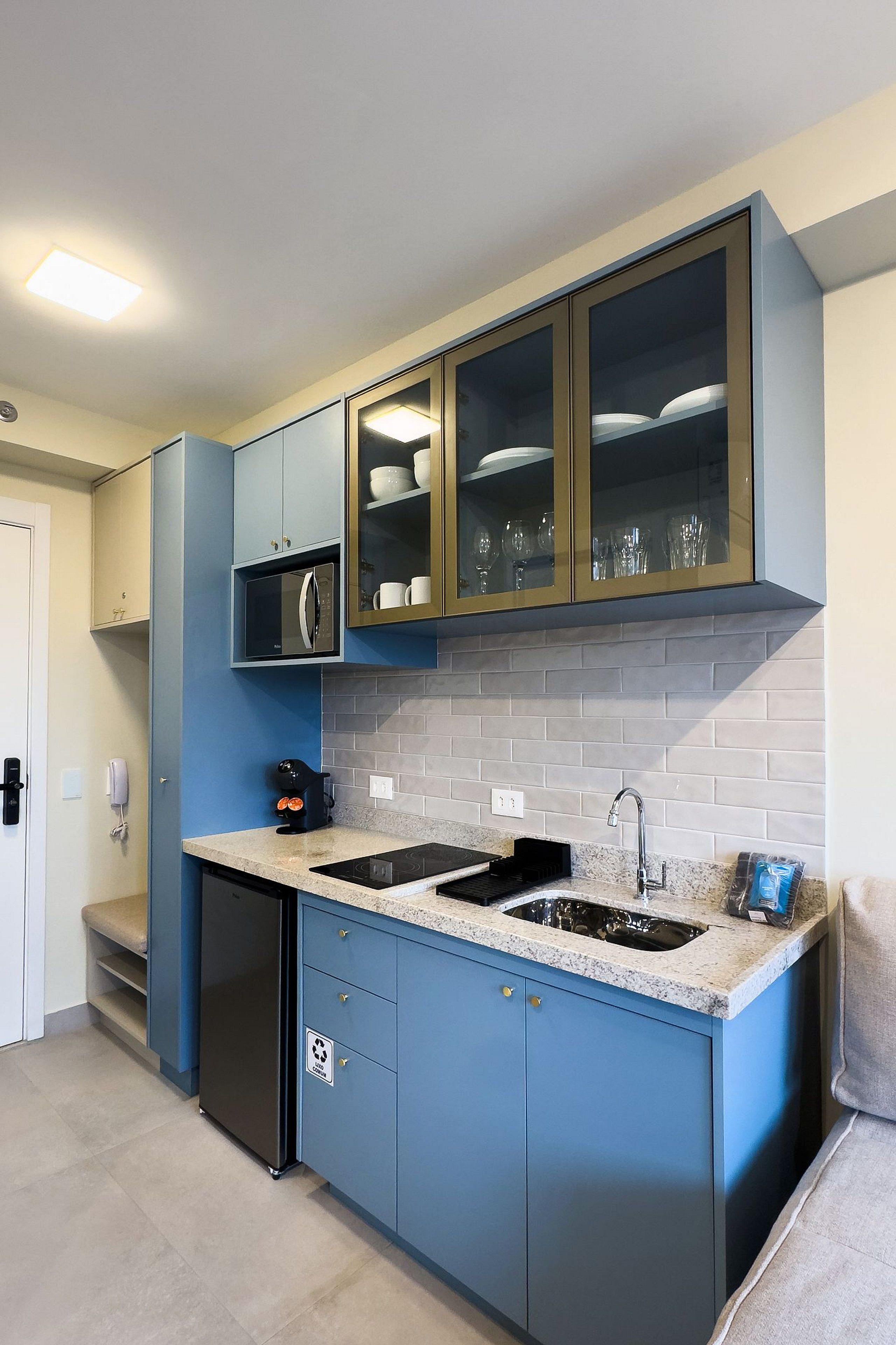A modern kitchen with blue cabinets, a built-in microwave, and a sink.