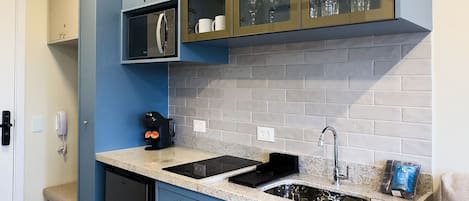 Una cocina moderna con armarios azules, microondas integrado y un lavabo.