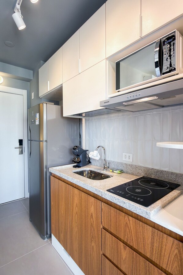 A modern kitchen with stainless steel appliances, a wooden cabinet, and a built-in microwave. - Temporada Express (São Paulo)