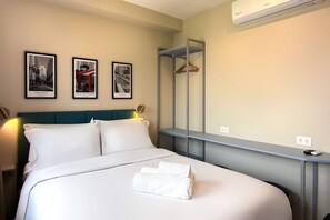 Ein Hotelzimmer mit einem Bett, einem Schreibtisch, einem Spiegel und zwei gerahmten Bildern an der Wand.