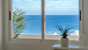 A window with a view of the ocean and a plant in the foreground. - Vacation Apartment 'Playa La Arena 2 Bed' with Sea View, Balcony and Wi-Fi (Puerto de Santiago)