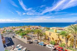 A coastal town with buildings, palm trees, and a clear blue sky.