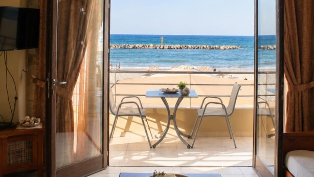 A room with a beach view, a table with a basket, a sofa, and a television. - Xristinas Apartments - Aphrodite Sea View (Kolymvari)