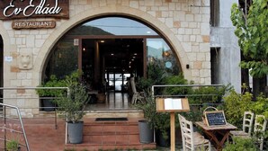 A restaurant entrance with an arched doorway, potted plants, and outdoor seating. - Xristinas Apartments - Aphrodite Sea View (Kolymvari)