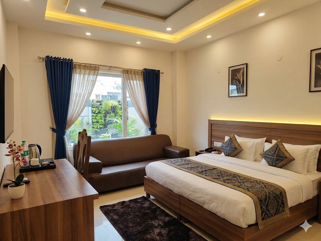Une chambre d’hôtel avec un lit, un canapé, un bureau et une fenêtre avec des rideaux.
