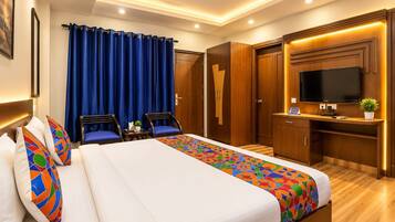 A hotel room with a bed, a desk, a television, and a ceiling fan.