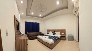 Ein modernes Hotelzimmer mit einem Bett, einem Schreibtisch, einem Fernseher und einem Deckenventilator.
