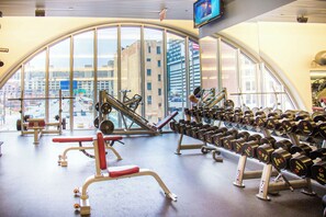 A gym with large windows, exercise equipment, and a view of the cityscape. - The Buckingham Athletic Club & Hotel (Chicago)