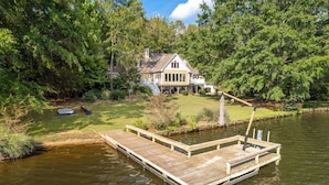 Une maison avec une jetée qui s’avance sur un lac, entourée d’une forêt dense.