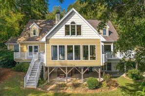 A two-story house with a covered porch, a staircase, and a large windowed front section. - Spacious Lakefront Retreat with Canoe & Views (Hillsborough)
