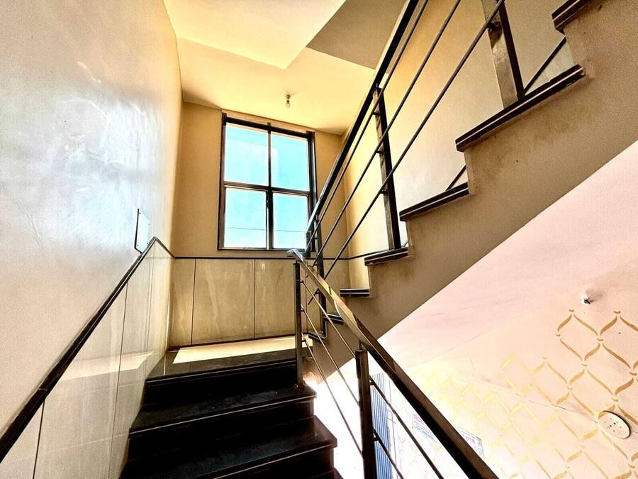 A modern staircase with glass railings and a large window at the top.