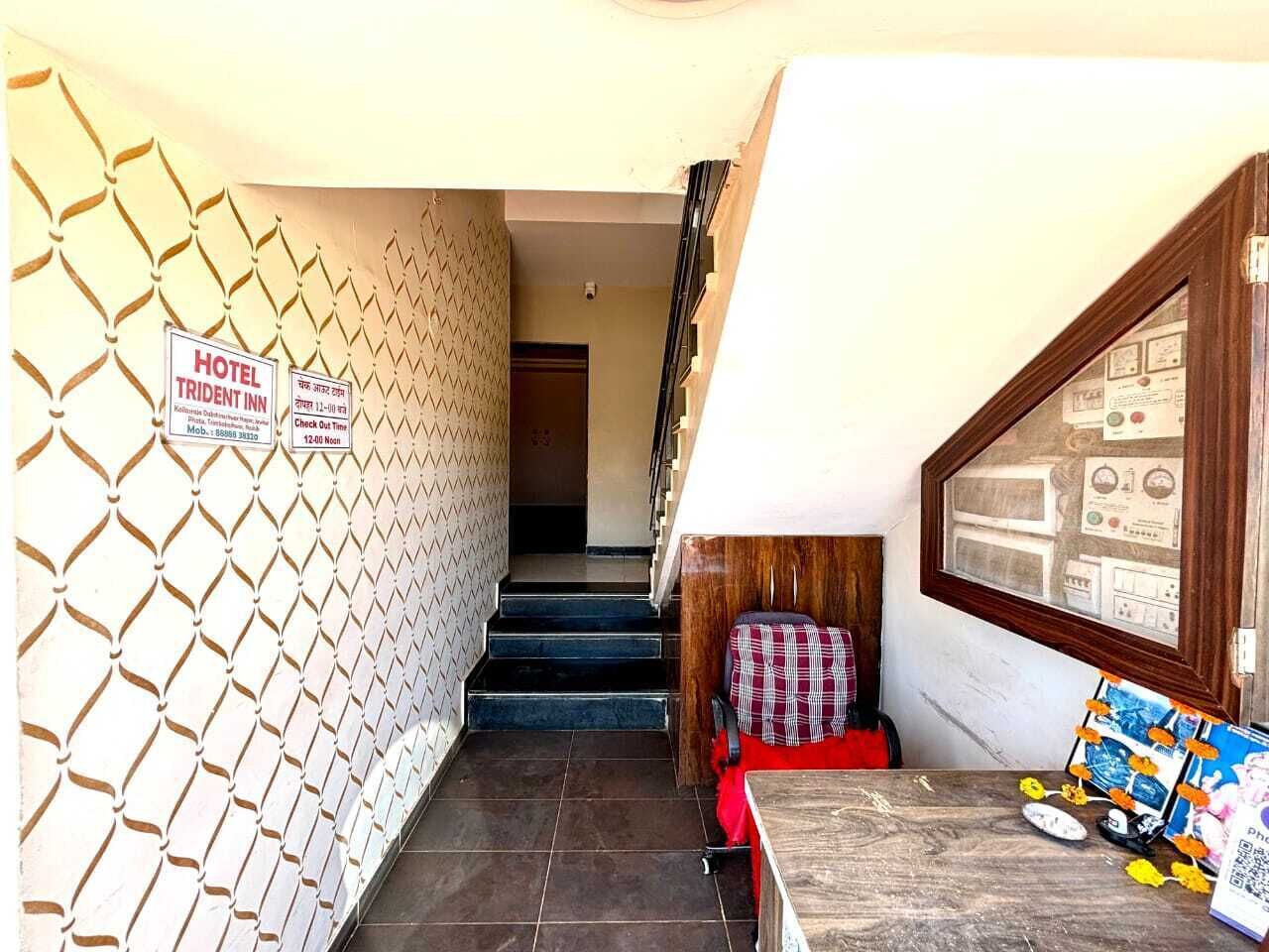 A hotel lobby with a check-in counter, a staircase, and a wall with a geometric pattern.