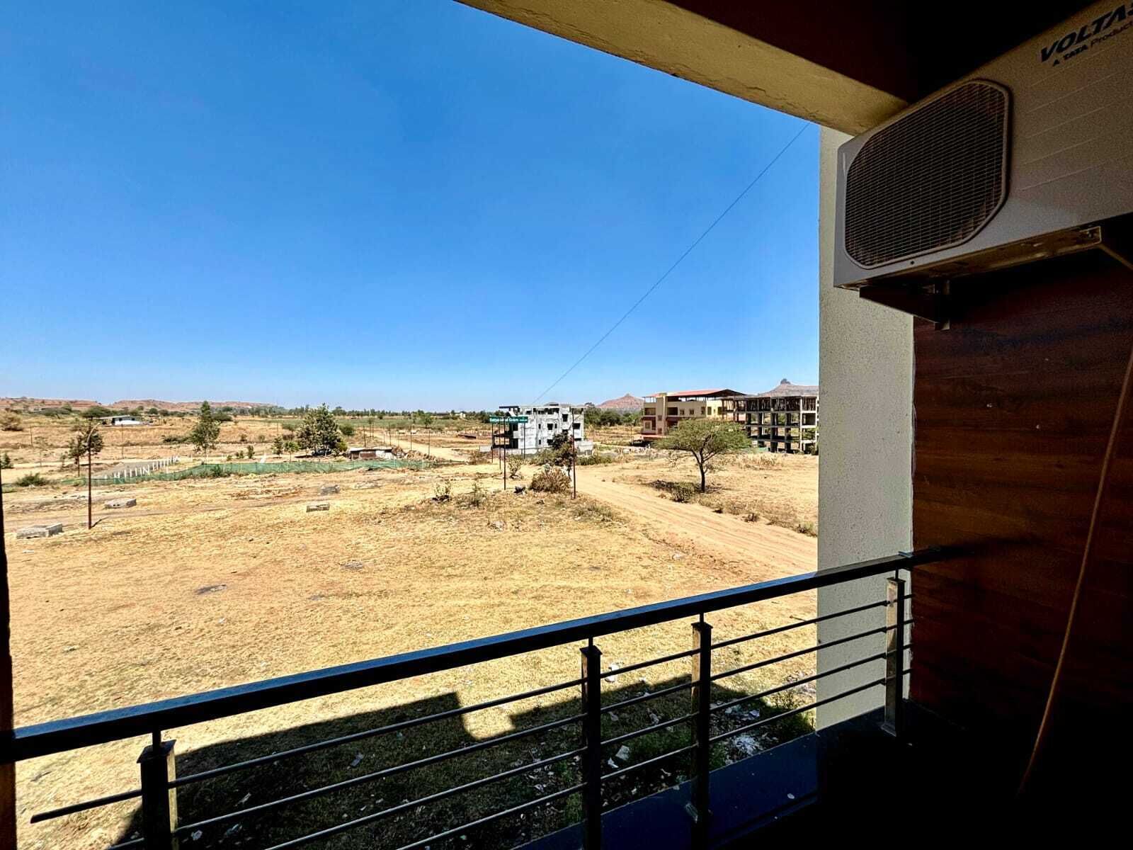 Un balcón con vistas a un paisaje árido y extenso, y edificios a la distancia.