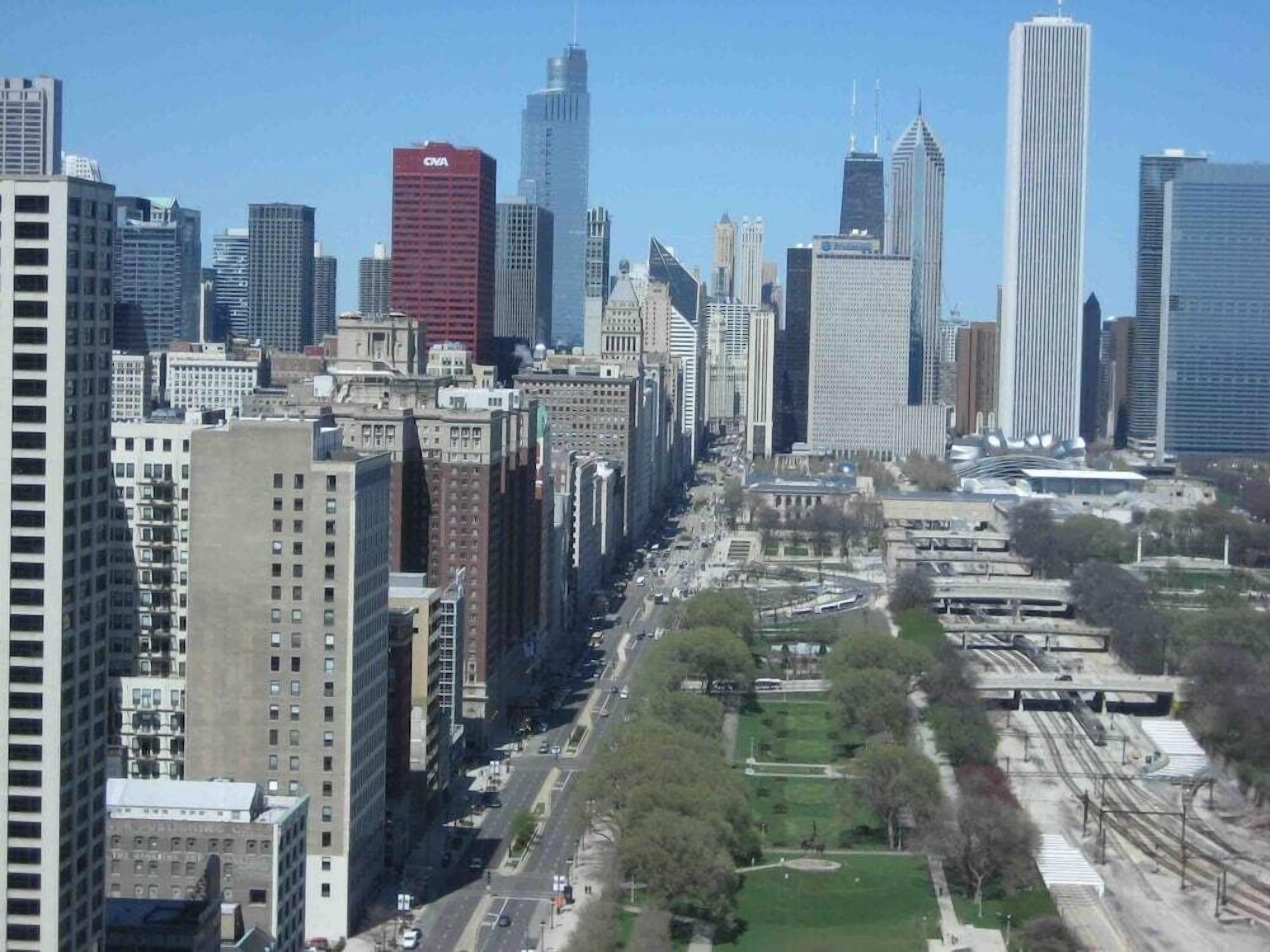 Un paisaje urbano con rascacielos, un parque central y un sistema ferroviario.