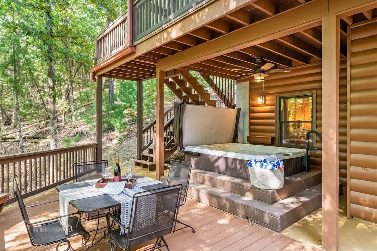 A wooden cabin with a deck, outdoor seating, and a hot tub.