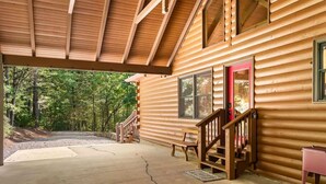 A log cabin with a covered porch, a red door, and a staircase leading to the entrance. - Luxury Cabin w/ Spa, Firepit & Game Room (Blue Ridge)