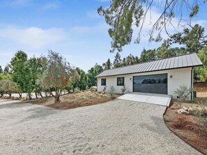 A modern single-story house with a garage, surrounded by a gravel driveway and sparse vegetation.