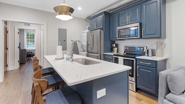 A modern kitchen with a central island, stainless steel appliances, and dark blue cabinetry. - Stylish, Downtown Charleston 2bd Home w. Porch! (Charleston)