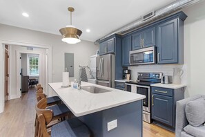 A modern kitchen with a central island, stainless steel appliances, and dark blue cabinetry.