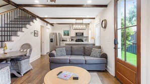 A modern living room with a grey sofa, a wooden coffee table, and a staircase with dark wooden railings. - 2bd Home, Large Private Backyard + Blocks to King! (Charleston)