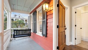 A porch with a wooden bench, a red wall, and a white door.