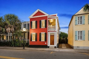 A two-story building with a red facade, a balcony, and a front door marked with the number 81. - Renovated 2bd Retreat, Steps to King. (Charleston)