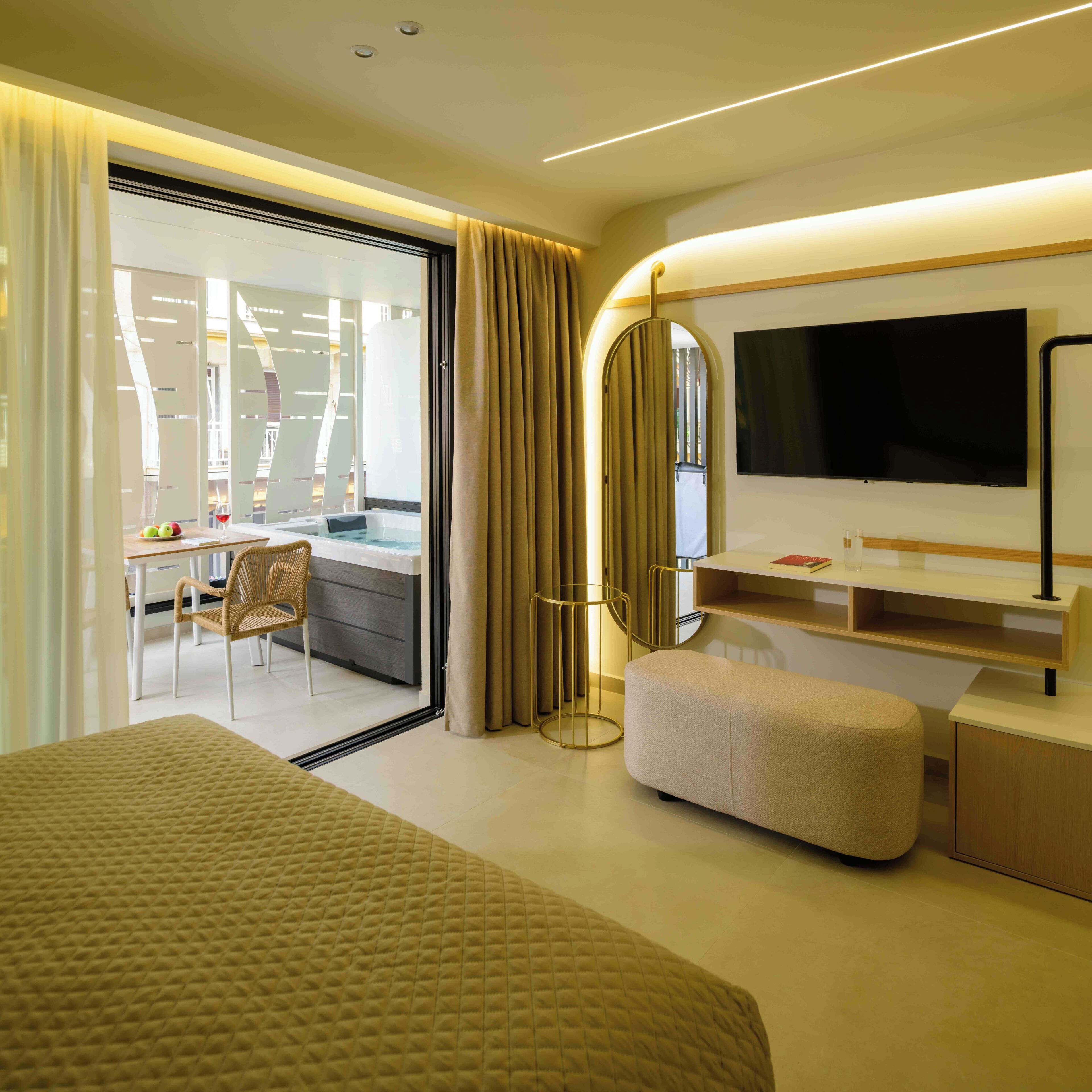 A modern hotel room with a large bed, a TV, a desk with a chair, and a view of a balcony.