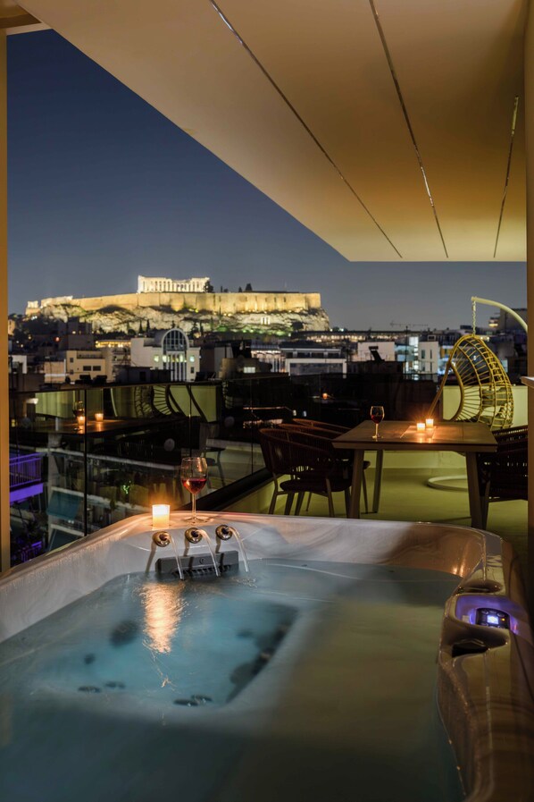Una terraza en la azotea con un jacuzzi, una mesa con velas y vistas a un edificio histórico al fondo.