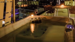 A rooftop terrace with a hot tub, a table with candles, and a view of a historic building. - Thea Acropolis Suites & Apartments (Athens)