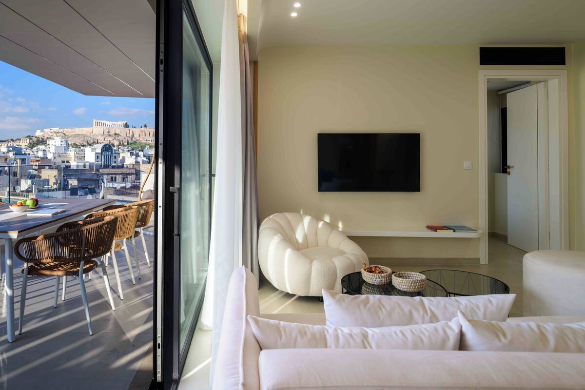 A modern living room with a sofa, a flat-screen TV, and a dining area with a table and chairs.