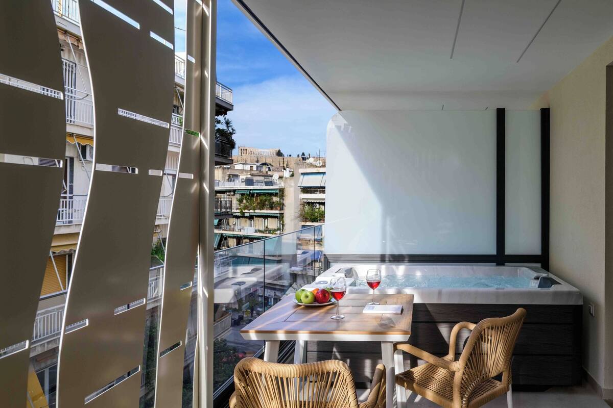 A balcony with a hot tub, a table with fruits and glasses, and wicker chairs.