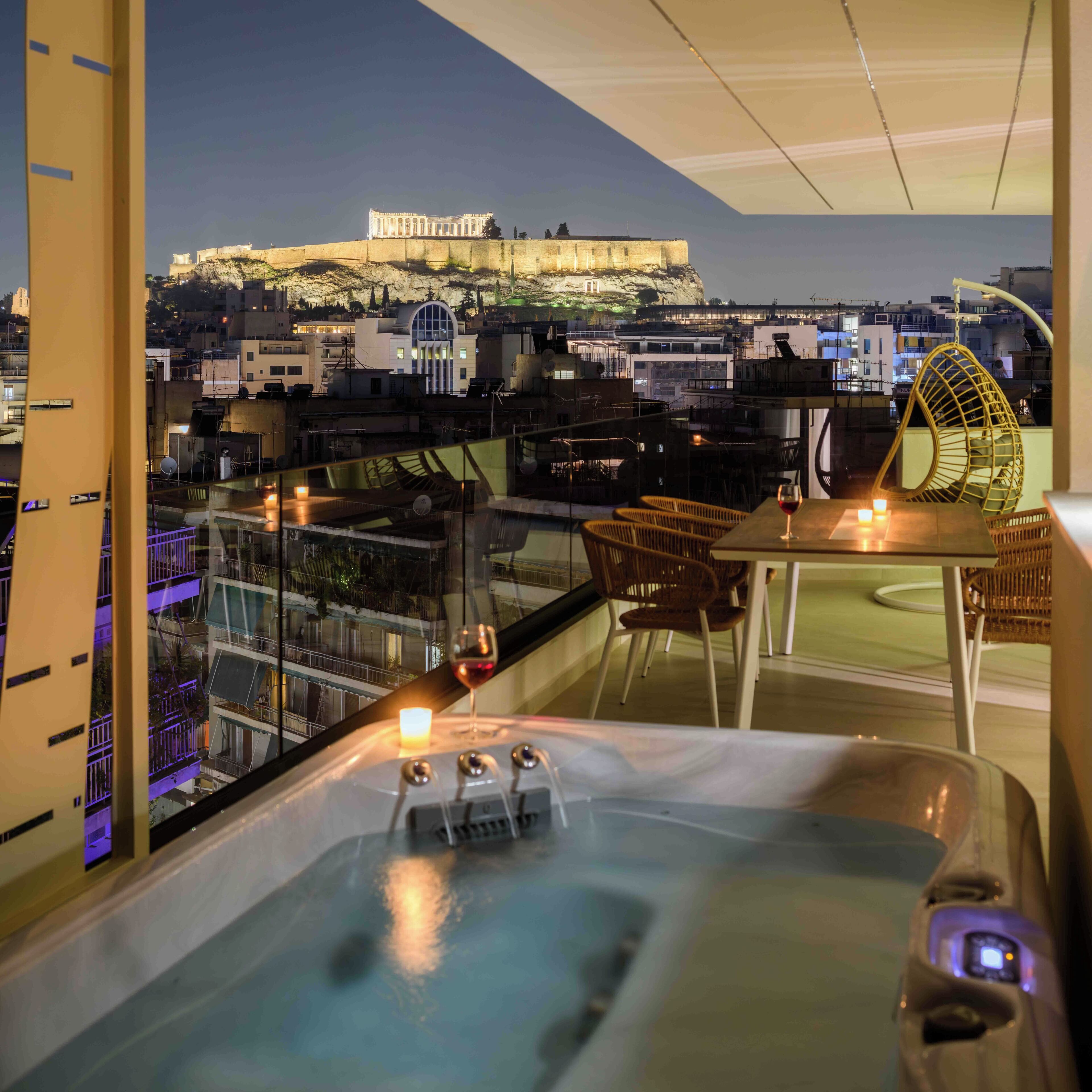 A balcony with a hot tub, wicker chairs, and a candle.