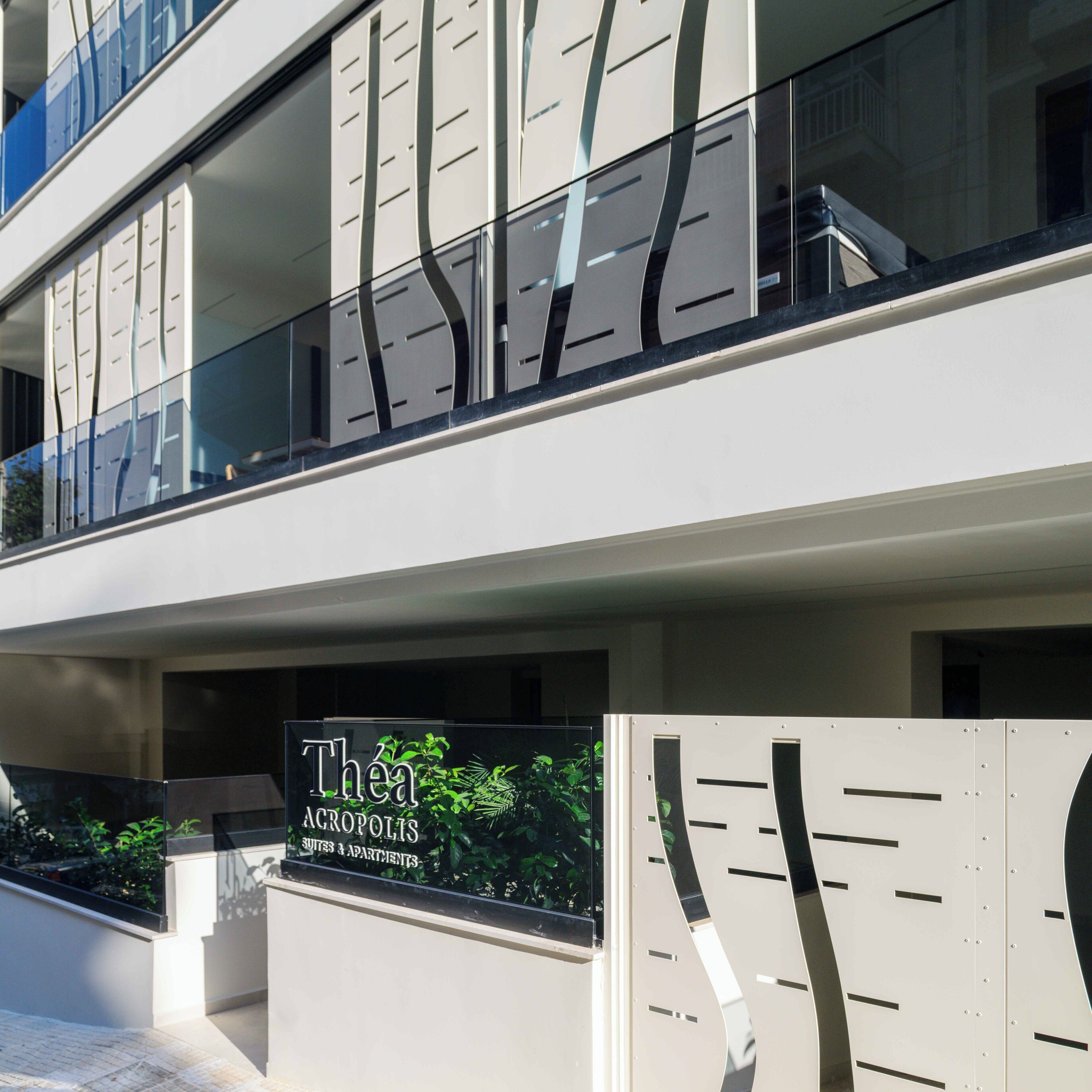Un edificio moderno con un letrero que dice "Théa Acropolis Suites & Apartments".
