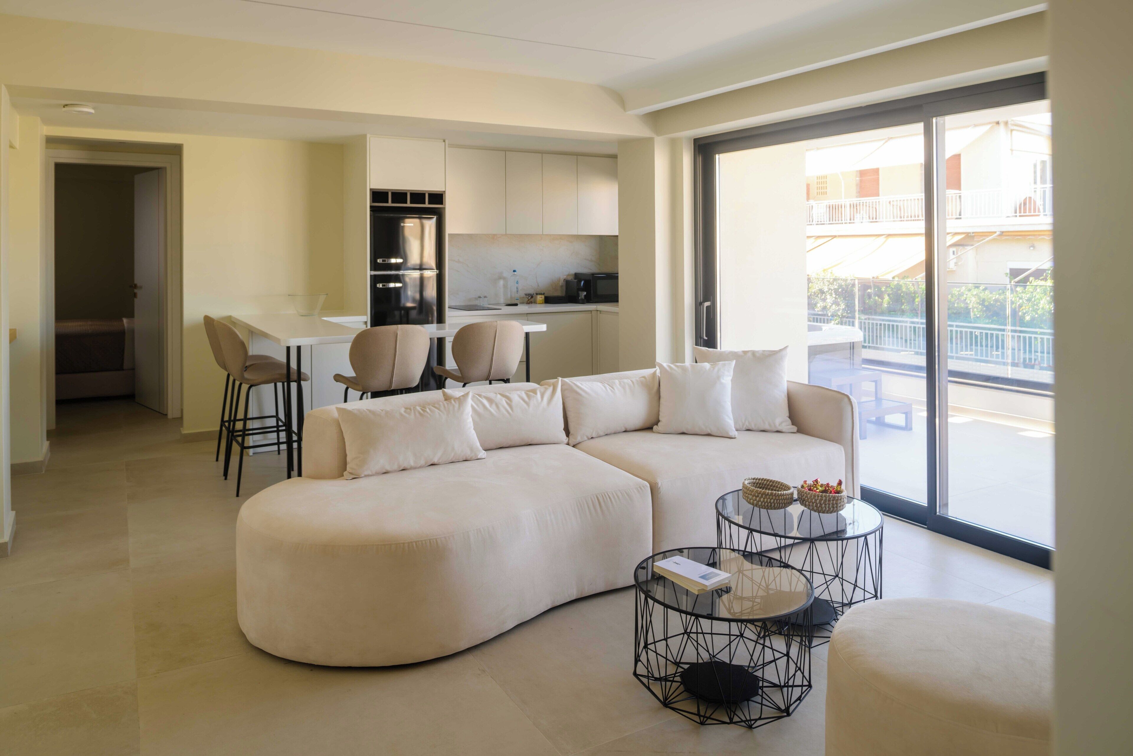 A modern living room with a sectional sofa, a dining area with chairs, and a kitchen in the background.