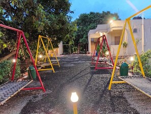 A playground with swings and a paved path. - Darsh Resort (Talala)
