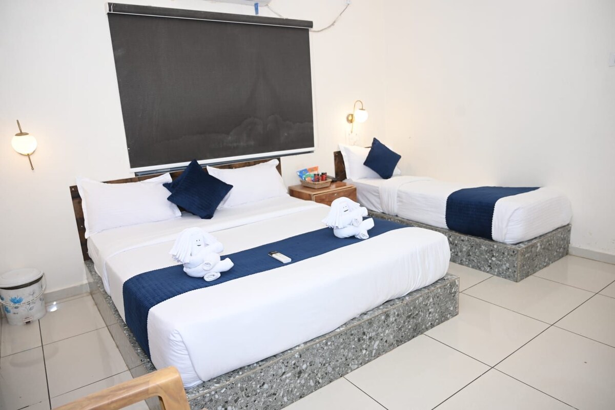 A hotel room with two beds, a large window, a small table, and a nightstand.