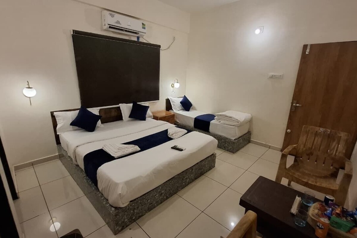 Une chambre d’hôtel avec un grand lit, deux tables de chevet, une chaise en bois, une petite table et une armoire.