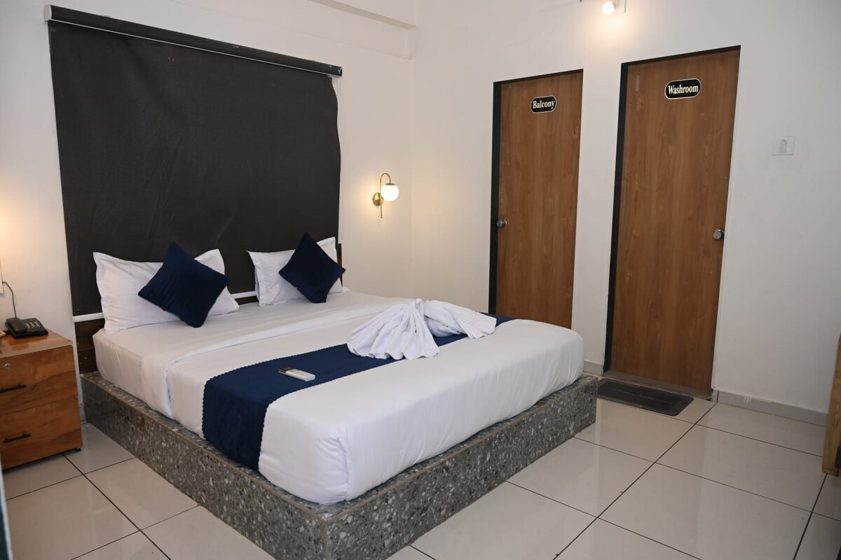 A hotel room with a bed, a nightstand, a washroom, and a balcony.