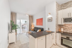 Una cocina moderna con microondas, horno y una isla. Hay un comedor con mesa y sillas.