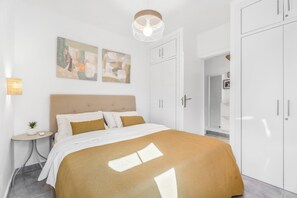 Ein modernes Schlafzimmer mit einem Bett, einem Nachttisch mit Lampe und abstrakten Wandbildern.