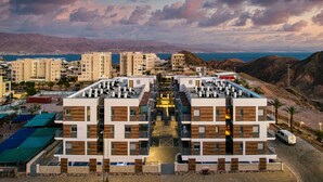Un hotel moderno con un ampio atrio centrale, diversi piani e vista sul mare e sulle montagne sullo sfondo.