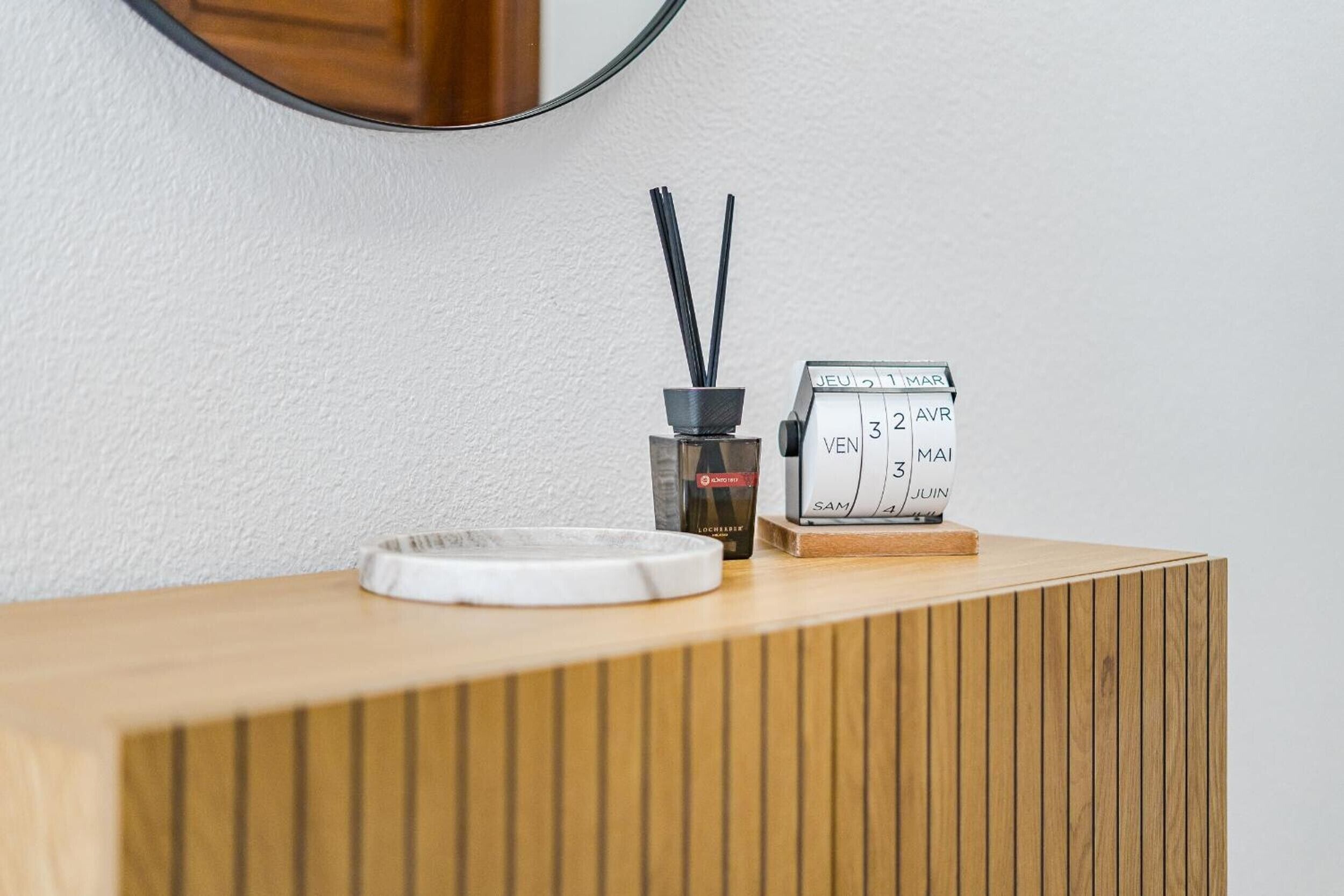 A wooden counter with a white tray, a black incense burner, and a small calendar.