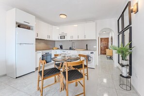 A modern kitchen with white cabinets, a dining table with chairs, and a central island.